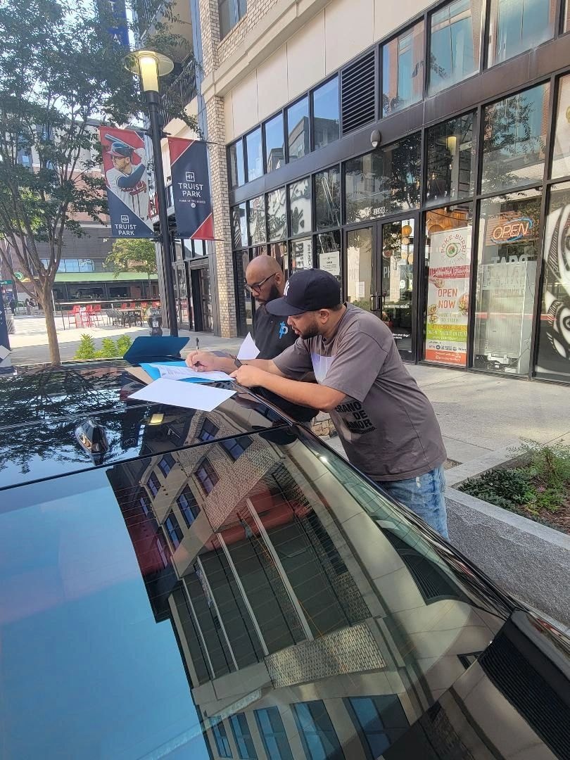 Will delivering XSE, two men reviewing documents over blue car hood